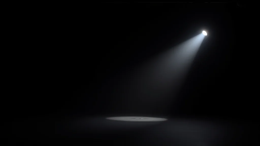 An empty studio backdrop with a single hard flash key light, glowing on dark